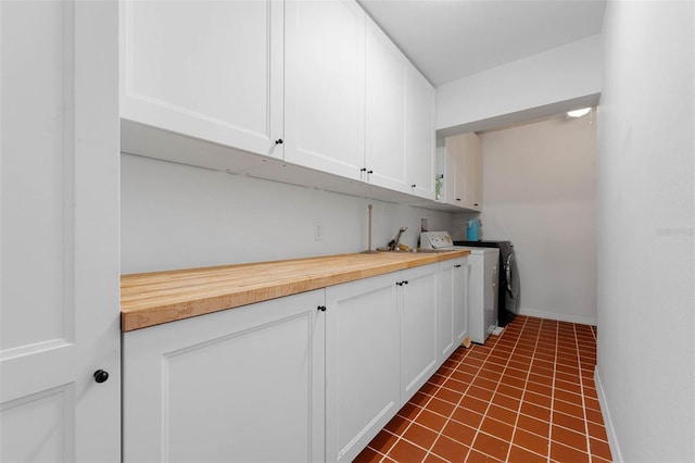 926 Mayfair Cir, Orlando, FL 32803 - laundry area with baseboards, dark tile patterned flooring, a sink, cabinet space, and separate washer and dryer