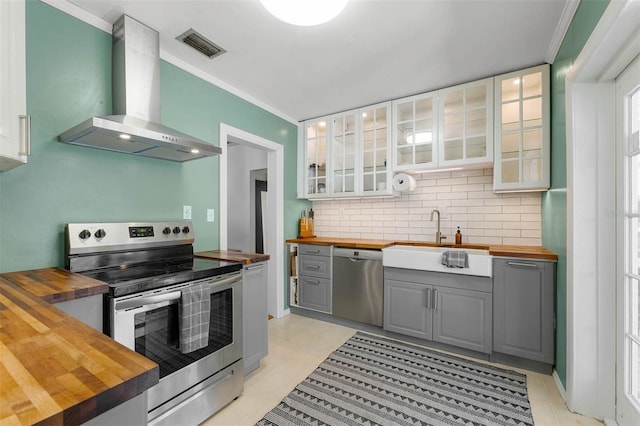 926 Mayfair Cir, Orlando, FL 32803 - kitchen with wood counters, wall chimney range hood, gray cabinets, and appliances with stainless steel finishes