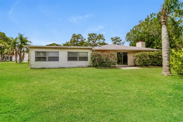 4337 Marine Pkwy, New Port Richey, FL 34652 - rear view of property featuring a lawn and a chimney