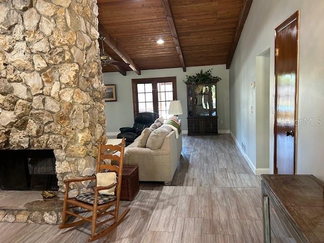 1500 Markham Woods Rd, Longwood, FL 32779 - living area with a stone fireplace, baseboards, lofted ceiling with beams, and wood ceiling