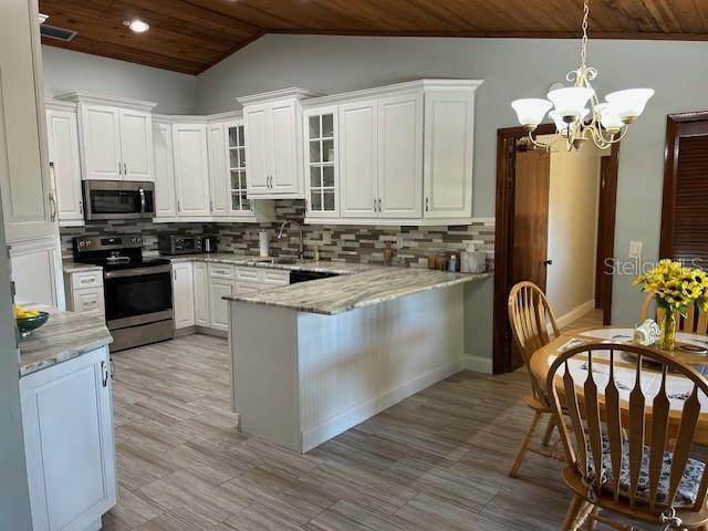 1500 Markham Woods Rd, Longwood, FL 32779 - kitchen featuring stainless steel appliances, backsplash, wood ceiling, a peninsula, and a notable chandelier