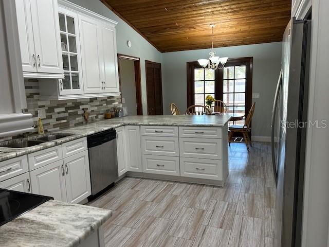 1500 Markham Woods Rd, Longwood, FL 32779 - kitchen with stainless steel appliances, white cabinetry, a sink, vaulted ceiling, and a notable chandelier