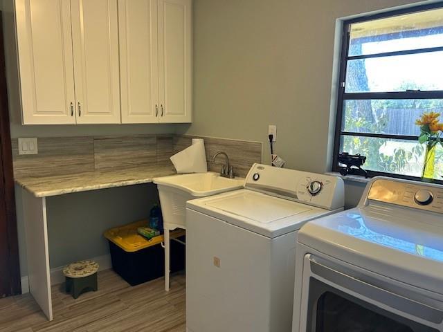 1500 Markham Woods Rd, Longwood, FL 32779 - laundry room with light wood finished floors, a sink, cabinet space, and separate washer and dryer