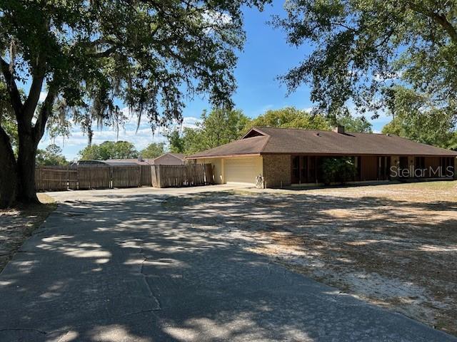1500 Markham Woods Rd, Longwood, FL 32779 - exterior space with driveway, an attached garage, fence, and a chimney