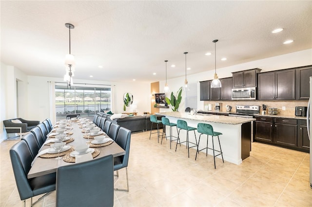 kitchen featuring a kitchen bar, stainless steel appliances, tasteful backsplash, a sink, and open floor plan