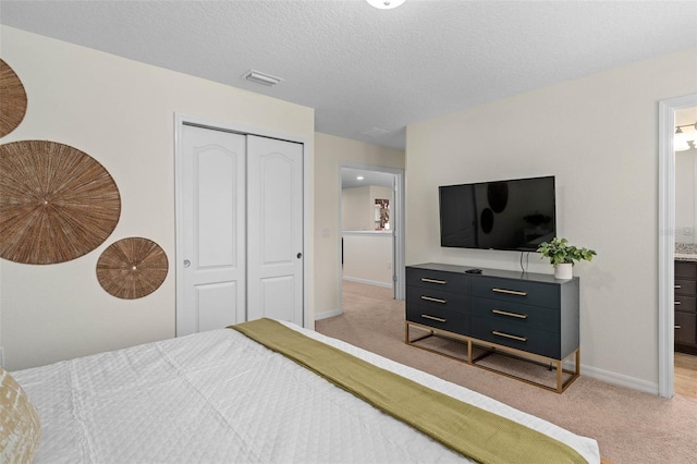 bedroom with a closet, light carpet, a textured ceiling, baseboards, and visible vents