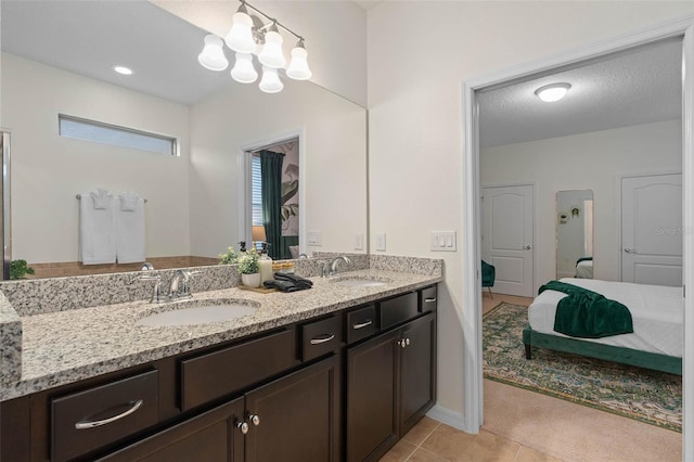 ensuite bathroom featuring a textured ceiling, double vanity, connected bathroom, and a sink