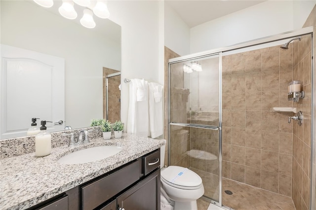 bathroom featuring toilet, vanity, and a stall shower