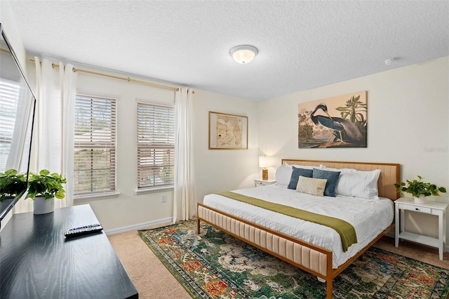bedroom with carpet, baseboards, and a textured ceiling