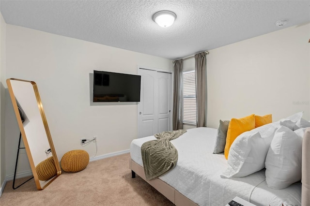 carpeted bedroom featuring a closet, a textured ceiling, and baseboards