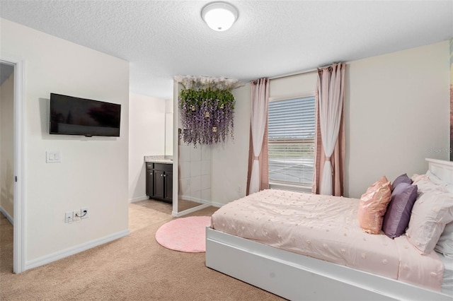 bedroom with baseboards, a textured ceiling, connected bathroom, and light colored carpet