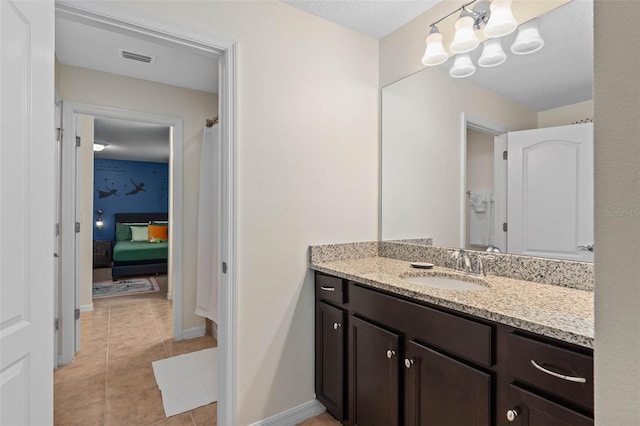 full bath featuring tile patterned flooring, vanity, baseboards, visible vents, and a notable chandelier
