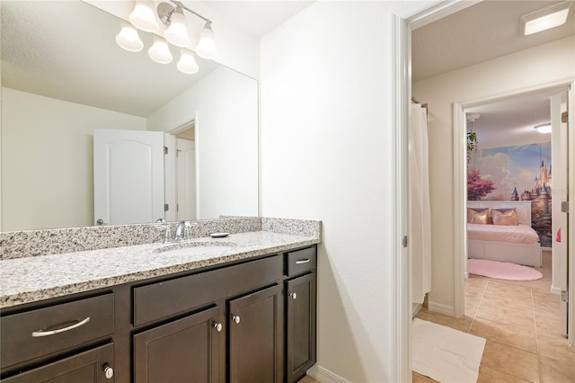 full bath with ensuite bathroom, baseboards, tile patterned flooring, and vanity
