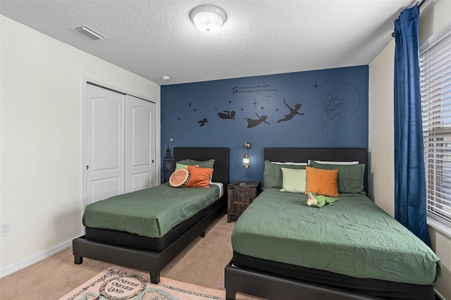 bedroom featuring carpet flooring, baseboards, a textured ceiling, visible vents, and a closet