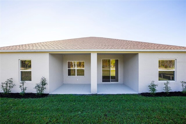 25372 Alicante Dr, Punta Gorda, FL 33955 - rear view of property featuring a yard, stucco siding, a patio area, and roof with shingles