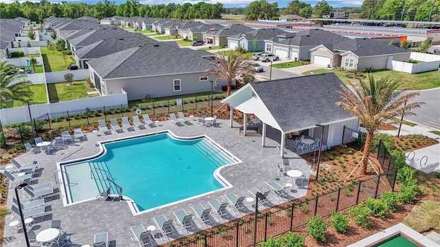 community pool featuring a patio area, fence, and a residential view