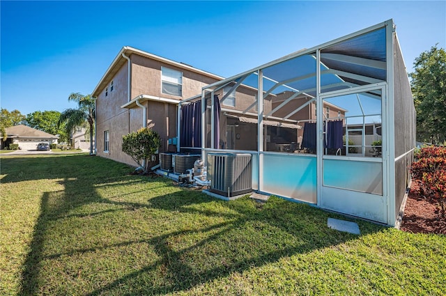 31028 Baclan Dr, Wesley Chapel, FL 33545 - back of house featuring stucco siding, glass enclosure, central AC unit, and a lawn