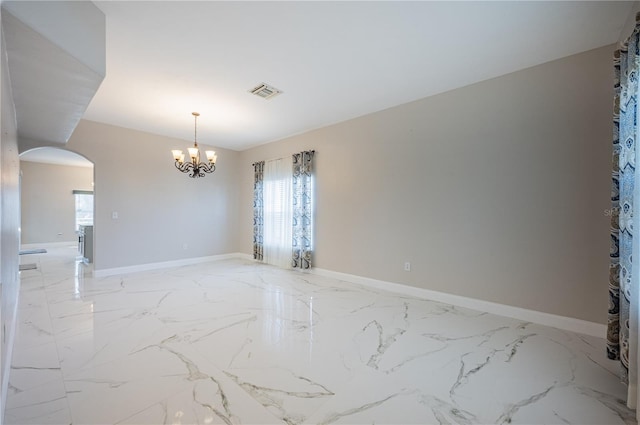31028 Baclan Dr, Wesley Chapel, FL 33545 - empty room with visible vents, baseboards, marble finish floor, arched walkways, and an inviting chandelier
