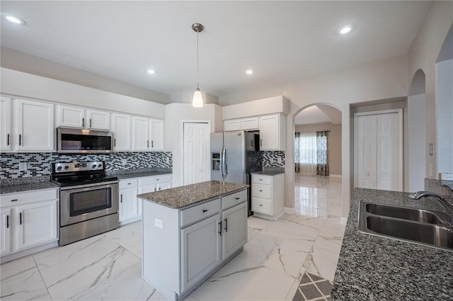 31028 Baclan Dr, Wesley Chapel, FL 33545 - kitchen featuring a sink, appliances with stainless steel finishes, a center island, marble finish floor, and arched walkways