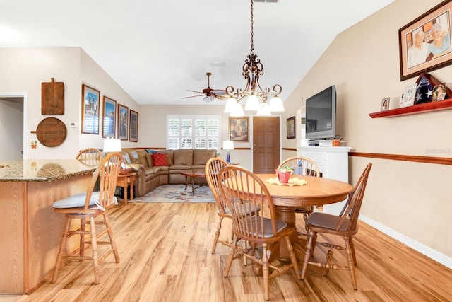 dining area featuring baseboards, light wood-style flooring, vaulted ceiling, and ceiling fan with notable chandelier