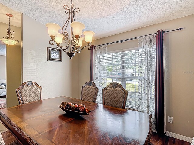 556 Hummingbird Ct, Kissimmee, FL 34759 - dining room featuring baseboards, dark wood-style floors, a textured ceiling, and an inviting chandelier