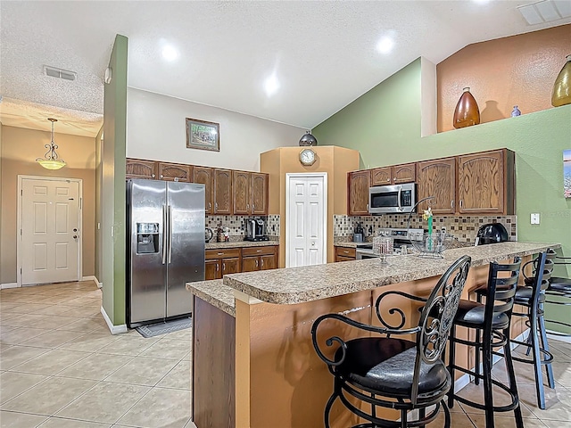 556 Hummingbird Ct, Kissimmee, FL 34759 - kitchen featuring a peninsula, decorative backsplash, light tile patterned floors, and stainless steel appliances