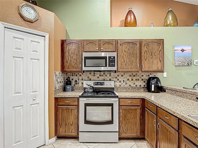 556 Hummingbird Ct, Kissimmee, FL 34759 - kitchen featuring light countertops, light tile patterned floors, appliances with stainless steel finishes, and decorative backsplash