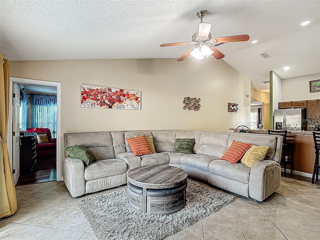 556 Hummingbird Ct, Kissimmee, FL 34759 - living room featuring vaulted ceiling, a textured ceiling, light tile patterned flooring, ceiling fan, and visible vents