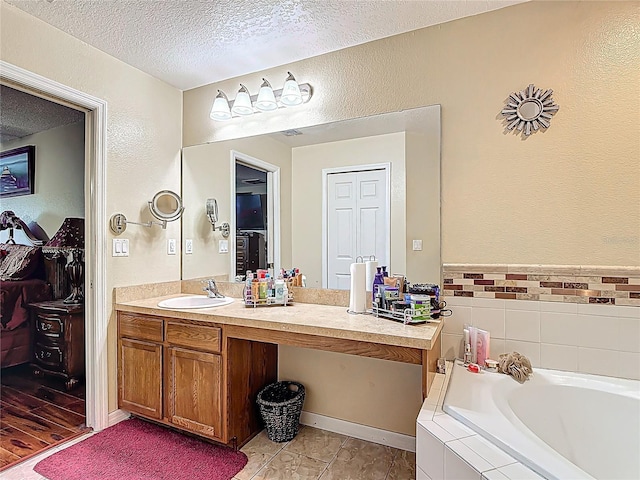 556 Hummingbird Ct, Kissimmee, FL 34759 - bathroom with a textured wall, vanity, a bath, and a textured ceiling