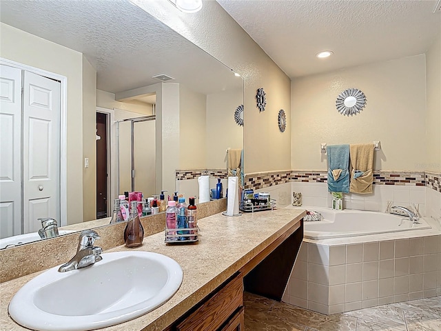 556 Hummingbird Ct, Kissimmee, FL 34759 - bathroom with a textured ceiling, visible vents, vanity, a stall shower, and a garden tub