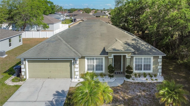 556 Hummingbird Ct, Kissimmee, FL 34759 - view of front of house featuring a garage, concrete driveway, a front lawn, roof with shingles, and stucco siding