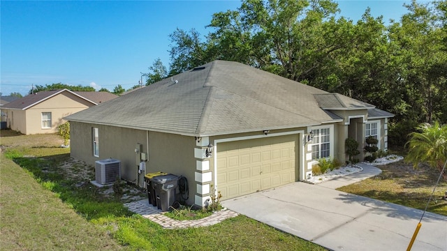 556 Hummingbird Ct, Kissimmee, FL 34759 - view of home's exterior with central air condition unit, a garage, roof with shingles, stucco siding, and a yard
