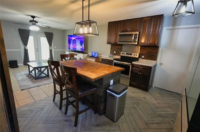 1491 Lavender St, Deltona, FL 32725 - kitchen with dark brown cabinetry, pendant lighting, a ceiling fan, appliances with stainless steel finishes, and decorative backsplash