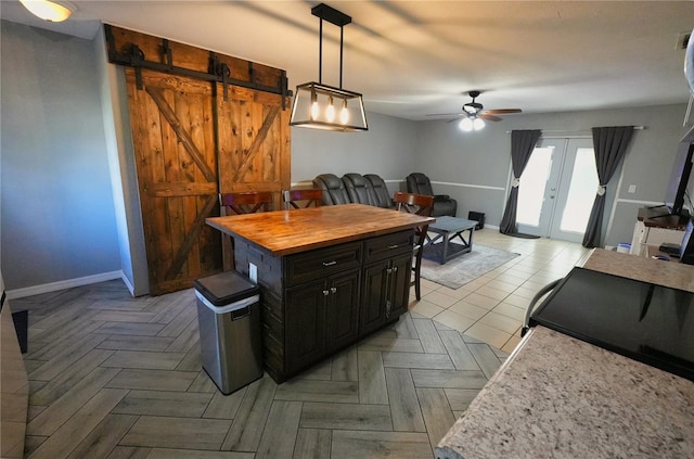 1491 Lavender St, Deltona, FL 32725 - kitchen featuring a ceiling fan, a barn door, dark cabinetry, baseboards, and wood counters