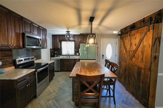 1491 Lavender St, Deltona, FL 32725 - kitchen featuring decorative backsplash, hanging light fixtures, a sink, dark brown cabinetry, and appliances with stainless steel finishes