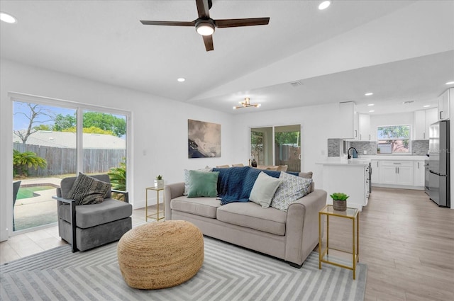 living room with recessed lighting, vaulted ceiling, and ceiling fan with notable chandelier