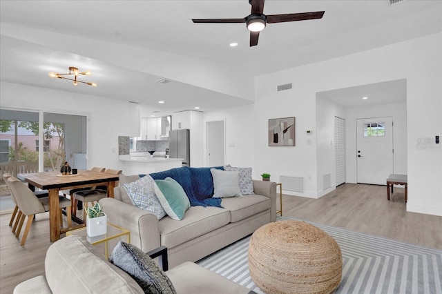 living room with light wood-style flooring, ceiling fan, and visible vents