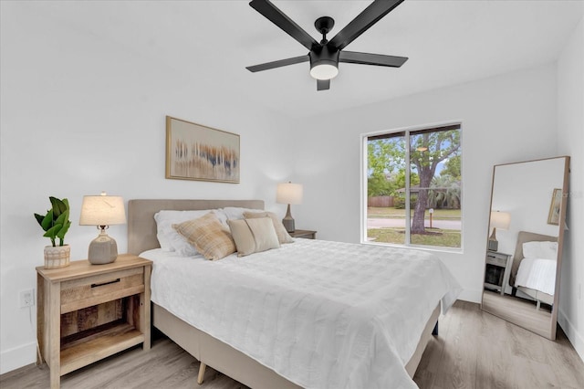 bedroom featuring light wood-type flooring, baseboards, and a ceiling fan