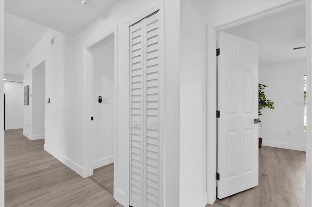 corridor featuring visible vents, baseboards, and light wood finished floors