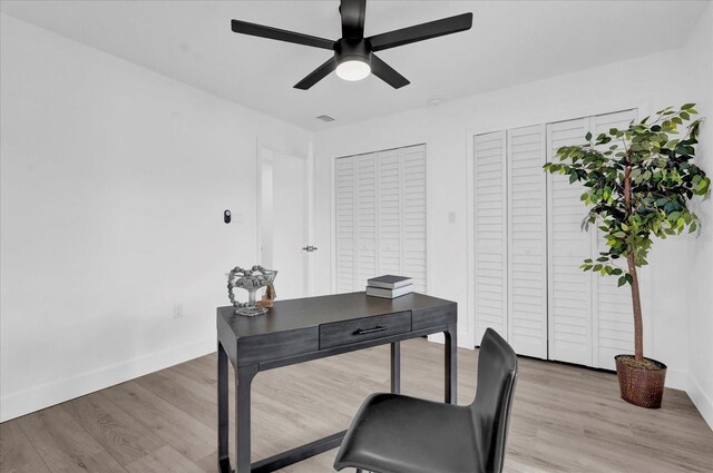 office space with light wood-style flooring, baseboards, a ceiling fan, and visible vents