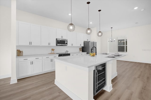 927 City Walk Ln, Oviedo, FL 32765 - kitchen with light countertops, wine cooler, a center island with sink, appliances with stainless steel finishes, and white cabinetry