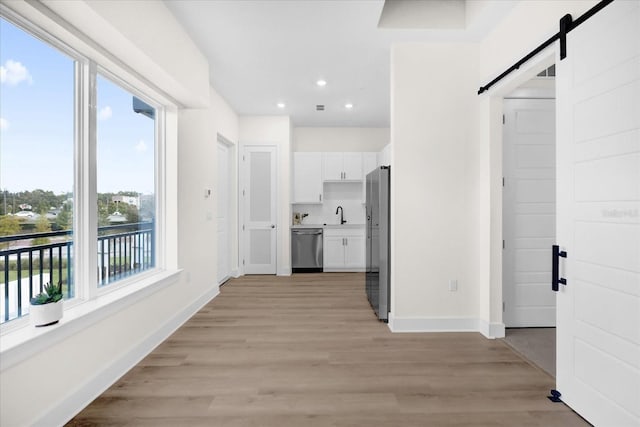 927 City Walk Ln, Oviedo, FL 32765 - hall with a sink, a barn door, light wood-style flooring, baseboards, and recessed lighting