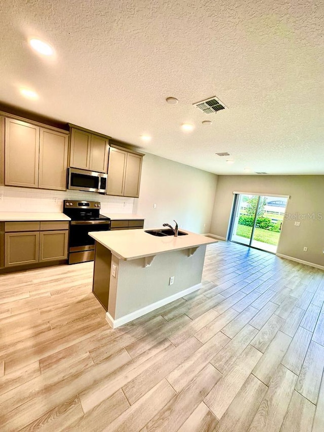 2834 Narcoossee Commons Way, Saint Cloud, FL 34771 - kitchen with appliances with stainless steel finishes, light wood-type flooring, open floor plan, a textured ceiling, and light countertops