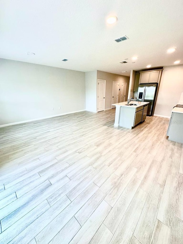 2834 Narcoossee Commons Way, Saint Cloud, FL 34771 - kitchen with stainless steel fridge, open floor plan, a center island with sink, light wood finished floors, and light countertops