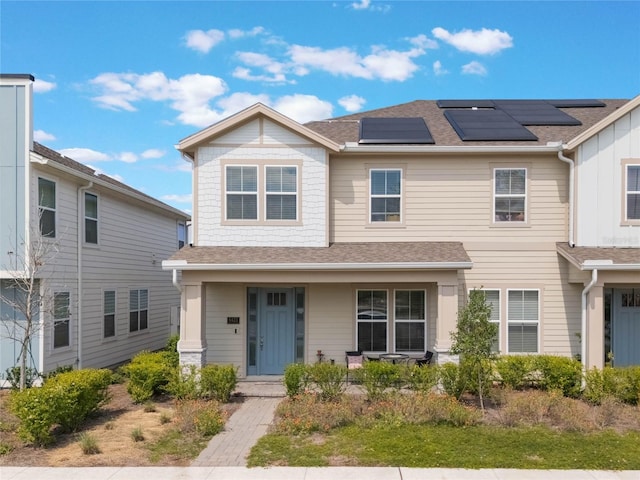 view of front of property with covered porch, roof with shingles, and roof mounted solar panels