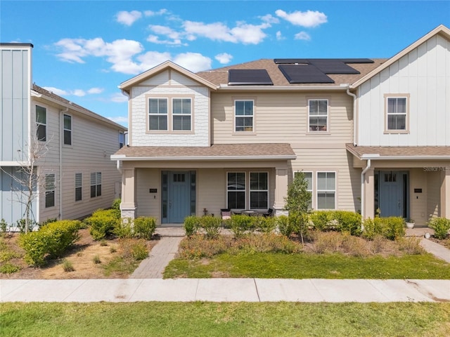 view of front of property with solar panels, a shingled roof, and a porch