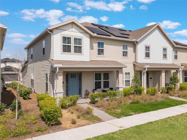 view of front of house with roof mounted solar panels, a porch, and roof with shingles