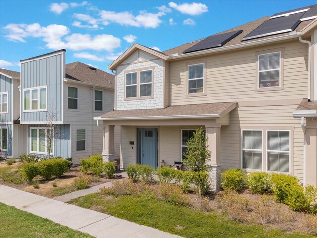 townhome / multi-family property with roof mounted solar panels and roof with shingles