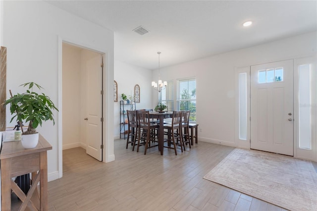 dining space featuring baseboards, visible vents, light wood-style floors, and an inviting chandelier