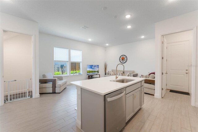 kitchen featuring open floor plan, a sink, light wood finished floors, and stainless steel dishwasher
